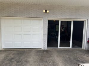 A white panel garage door installed next to a sliding glass door by PM Garage Door in Hudson, NH.
