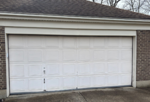 A classic white panel garage door on a brick residence, serviced by Overhead Door Company of Evansville in Evansville, IN.