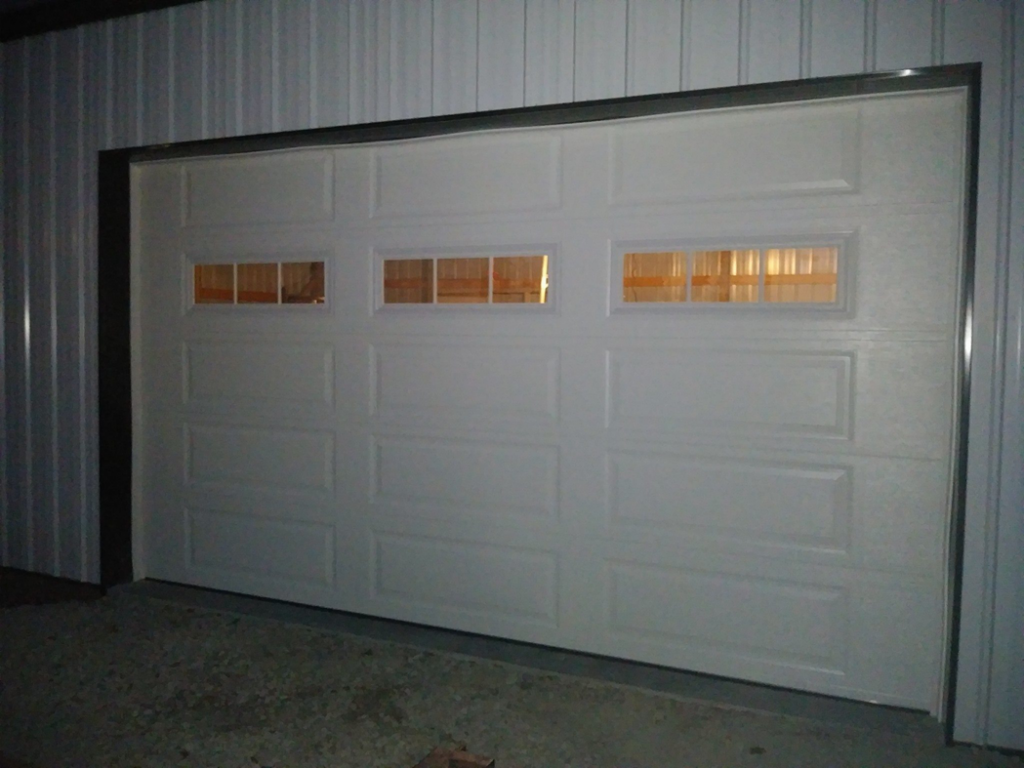 A white panel garage door with windows installed in a commercial building by R&A Overhead Door in Gower, MO.