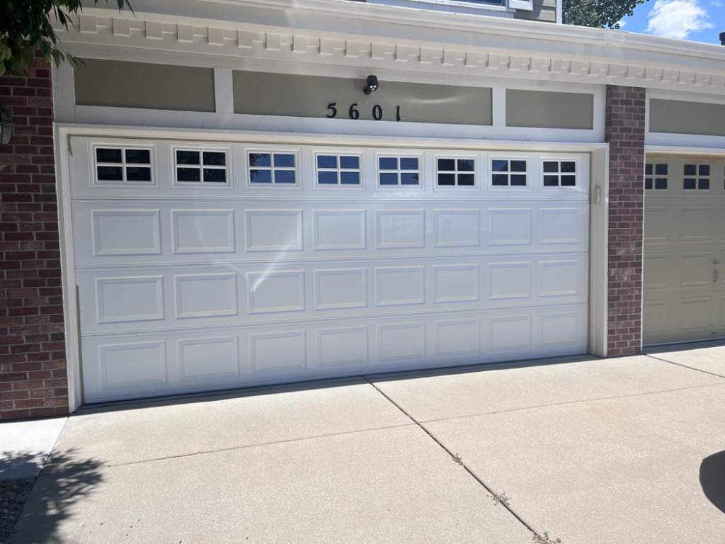 A pristine white panel garage door with decorative square windows, installed by Pham Garage Door Service & Repair in Arvada, CO.