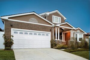 A brown house with a large white paneled garage door featuring arched windows by Overhead Door Company of Knoxville in Knoxville, TN