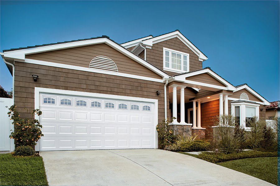 A brown house with a large white paneled garage door featuring arched windows by Overhead Door Company of Knoxville in Knoxville, TN