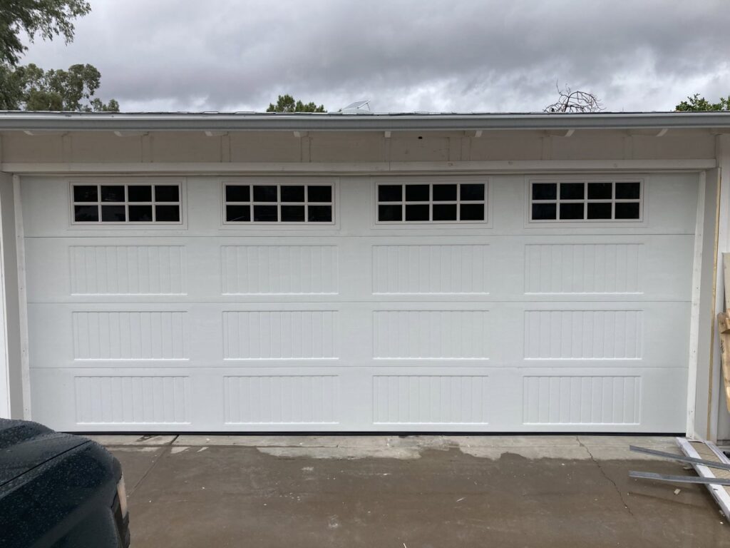 A newly installed white paneled garage door with top windows by Anew Garage by Jon's Garages in Surprise, AZ.