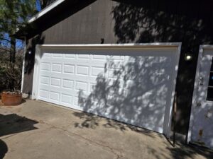 A white paneled garage door installed on a brown wooden building by LabraDoor Overhead Services in Eau Claire, WI.
