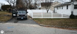 Installation of white picket and privacy fences with a work truck on site by Reilly Fence Inc in Cranston, RI.