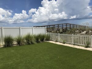 A backyard featuring white picket and privacy fences installed by Best Fence and Rail, with a boardwalk to the beach in Jacksonville, FL.