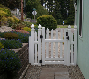 A classic white picket fence and gate installed next to a home, a quality project by West Coast Fencing in Coos Bay, OR.