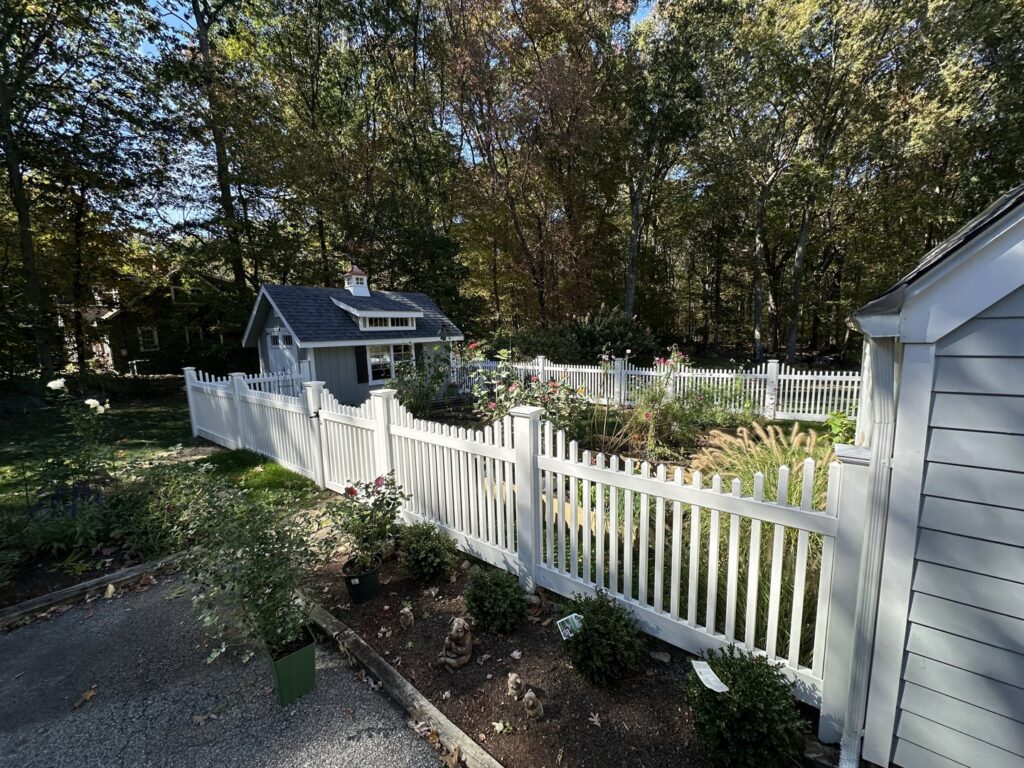 A charming white picket fence enclosing a garden area by Quality Fence Inc. in Peekskill, NY.