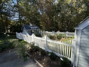 A charming white picket fence enclosing a garden area by Quality Fence Inc. in Peekskill, NY.