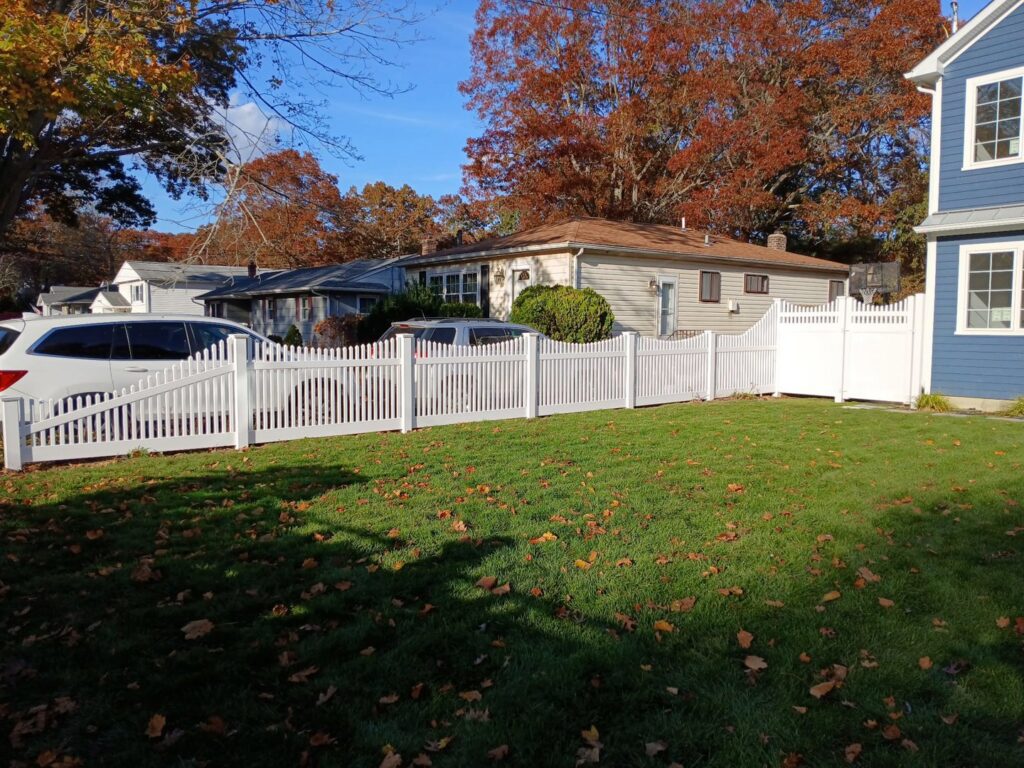 A charming white picket fence surrounding a residential yard, expertly installed by Zelaya Fence in New York City, NY.
