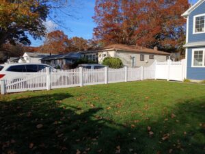 A charming white picket fence surrounding a residential yard, expertly installed by Zelaya Fence in New York City, NY.