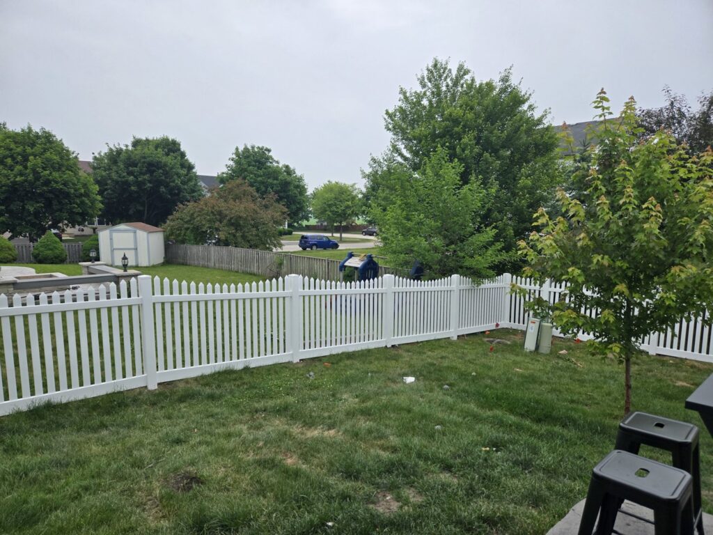 A white picket fence installed in a residential backyard by Cedar Mountain Fence Company in Plainfield, IL.