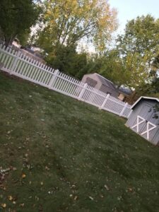 A white picket fence installed in a residential backyard next to a shed by Budget Fence of Ohio in Cleveland, OH.