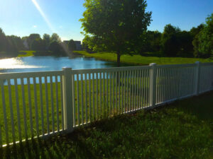 A white picket fence installed along the edge of a pond by AmeriDream Fence & Deck in Joliet, IL.