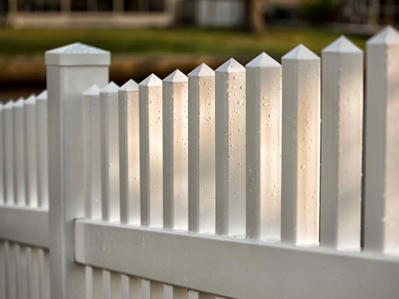A close-up view of a classic white picket fence, a quality installation by OneGuard Fencing in Vestavia Hills, AL.