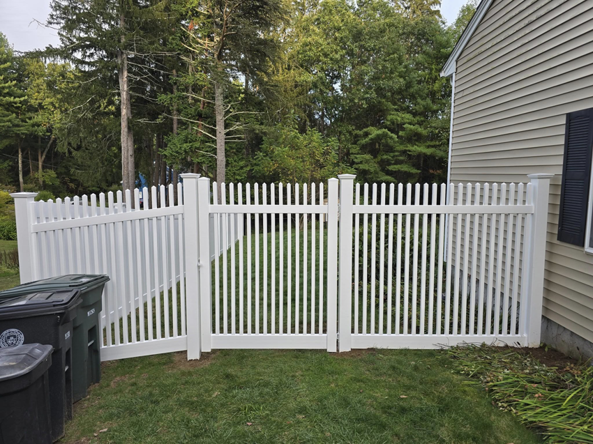 A white picket fence with a double gate installed next to a house by Homestead Fence in Cumberland, RI.