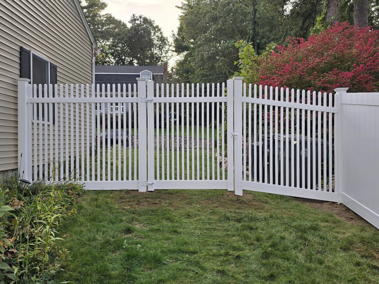 A white picket fence with a double gate, one panel slightly open, installed by Homestead Fence in Cumberland, RI.