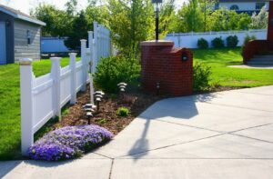 A white picket fence installed along a residential driveway by Western Fence in Hebron, ND.