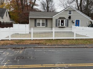 A beautiful white picket fence installed in a front yard along a street by AVA Fence & Railing LLC in Stamford, CT.