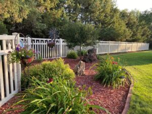 A white picket fence enclosing a beautiful garden area by Western Fence in Hebron, ND.