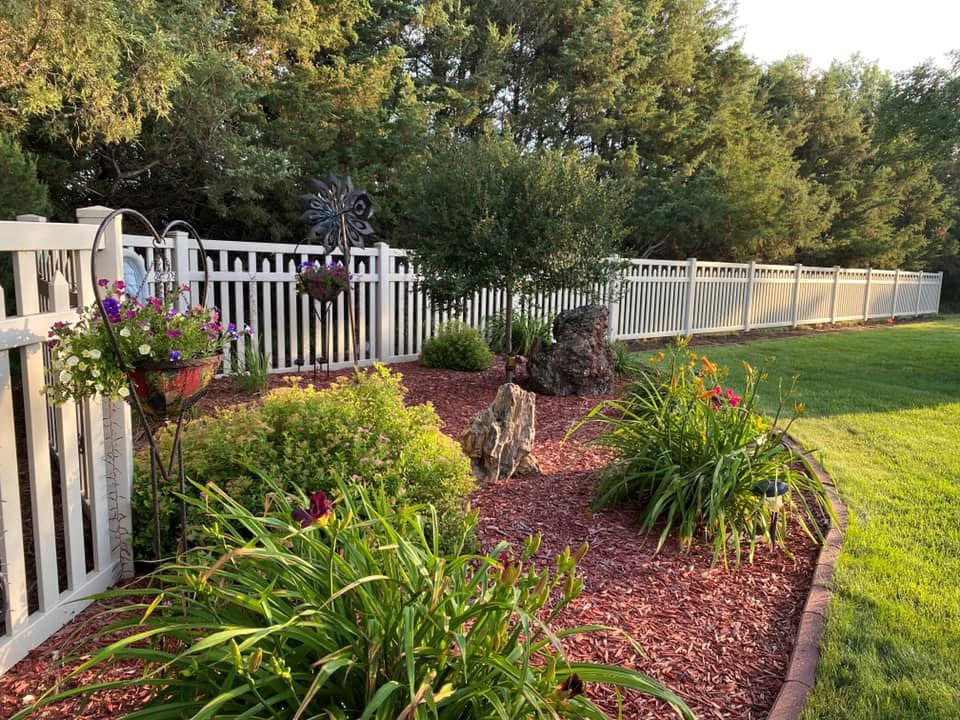 A white picket fence enclosing a beautiful garden area by Western Fence in Hebron, ND.