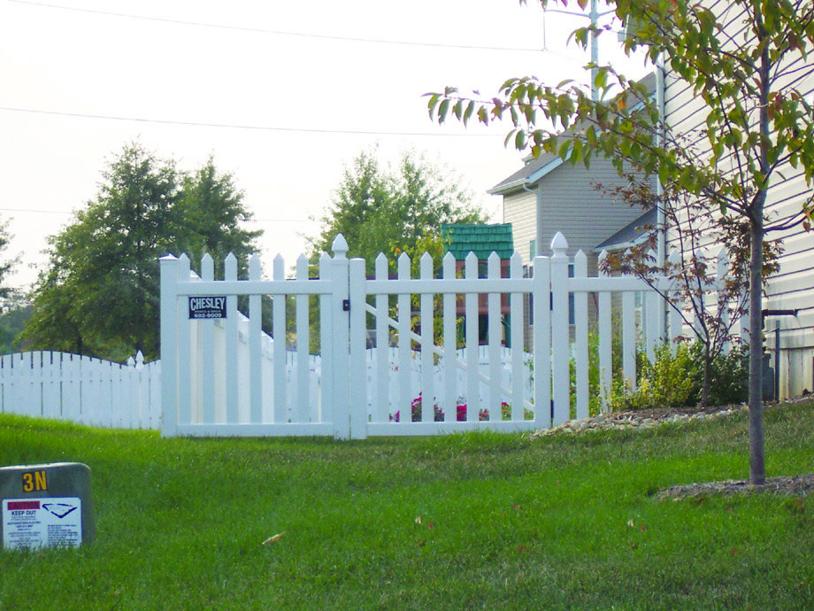 A charming white picket fence with a gate and a Chesley Fence sign, installed by Chesley Fence & Deck in Fairview Heights, IL.