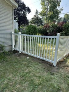 A white picket-style fence newly installed around the corner of a house by T & A Fencing in Warren, MI.