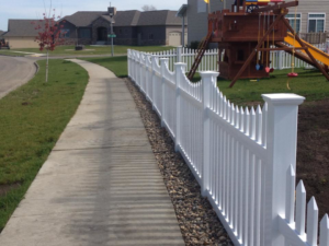 A newly installed white picket fence along a residential sidewalk by Elite Custom Fencing in Arthur, IL.