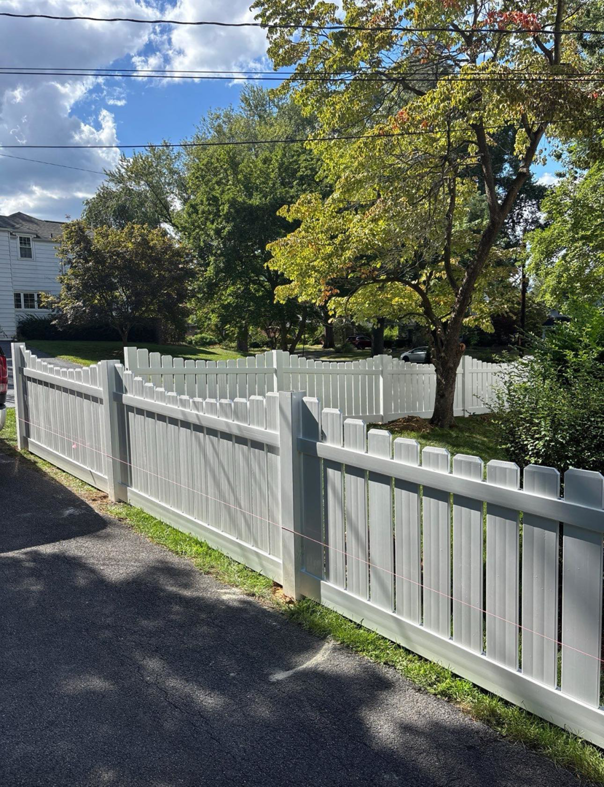 A newly installed white picket fence by Red Gate Fencing in Allentown, PA, enhancing a residential property.
