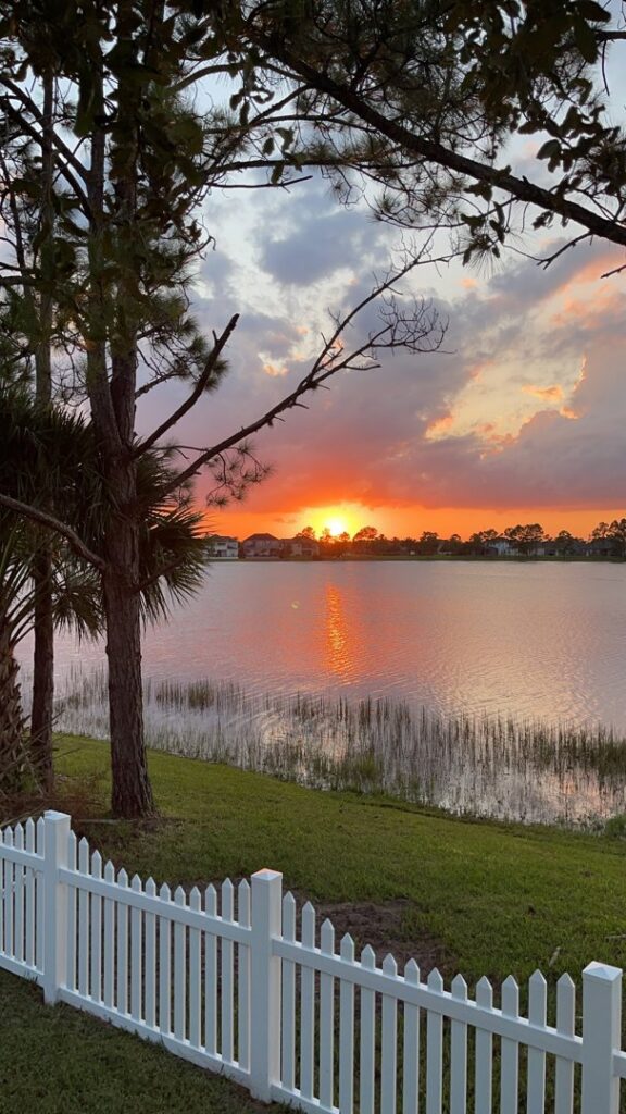 A picturesque white picket fence overlooking a serene lake at sunset, installed by Inovation Fence in Fort Worth, TX.