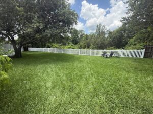 A charming white picket fence installed in a spacious backyard by Native Outdoors, LLC in Orlando, FL.