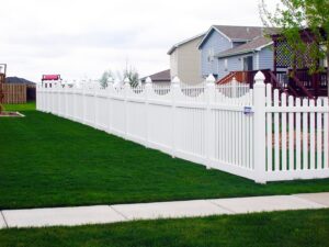 A classic white picket fence installed along a sidewalk in a residential area by American Fence Company - Omaha in Omaha, NE.