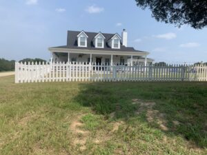 A classic white picket fence installed around a residential property by First Responder Outdoor Construction LLC in Bartlett, TN.