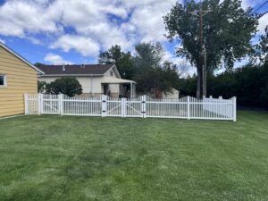 A white picket fence with two gates installed in a backyard by Western Fence in Hebron, ND.