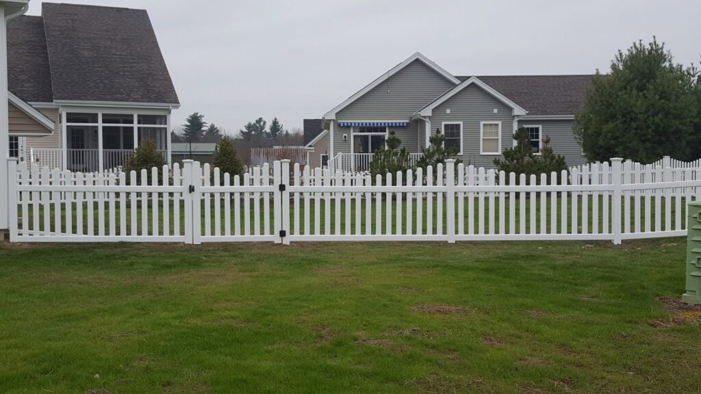 A classic white picket fence with a gate installed by 802 Fence Company LLC in Shoreham, VT.