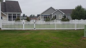 A classic white picket fence with a gate installed by 802 Fence Company LLC in Shoreham, VT.