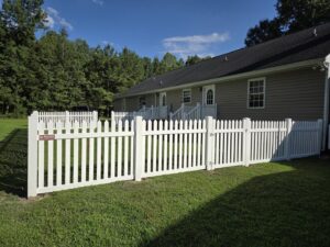 A charming white picket fence with a gate enclosing a backyard, installed by Superior Fence & Rail Richmond, VA.