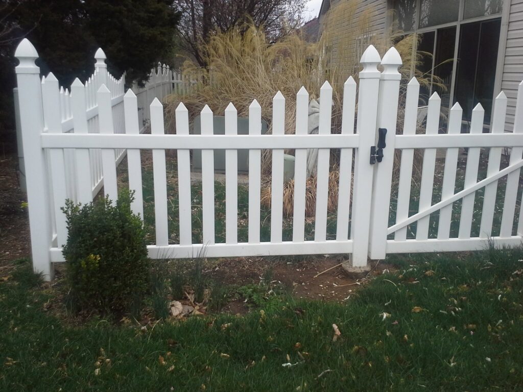 A classic white picket fence with a gate installed in a residential yard by Border Built Fencing in Florence, KY.