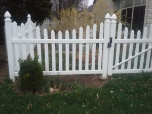 A classic white picket fence with a gate installed in a residential yard by Border Built Fencing in Florence, KY.