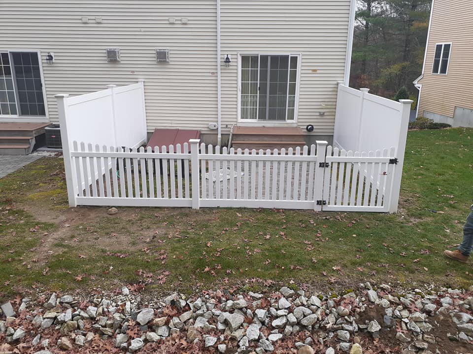 A charming white picket fence with a gate installed by D & G'S Maintenance LLC in Woonsocket, RI.