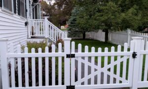 A classic white picket fence with a gate installed in front of a home by Precision Fence NH in Hooksett, NH.