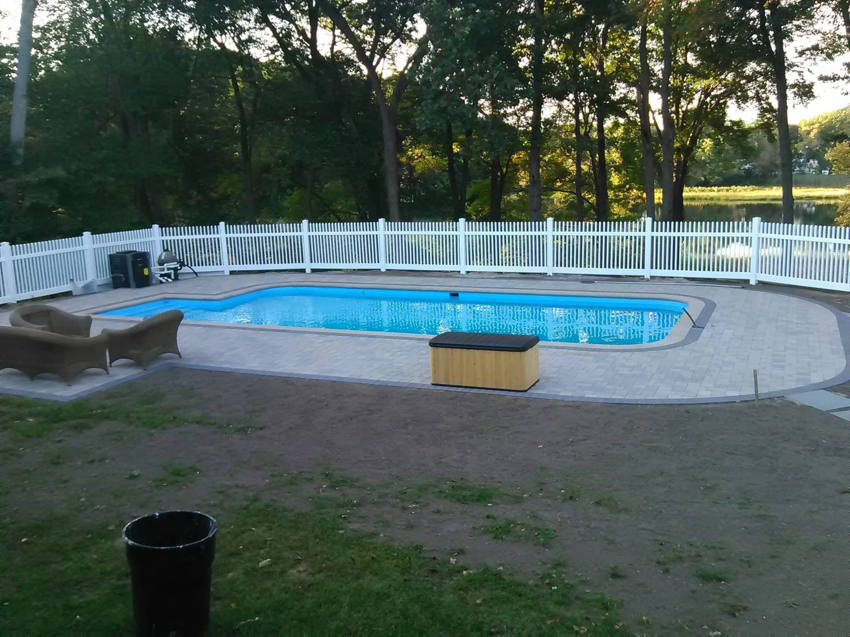 A white picket fence installed around a swimming pool for safety and aesthetics by Ocean State Fence Works LLC in North Kingstown, RI.