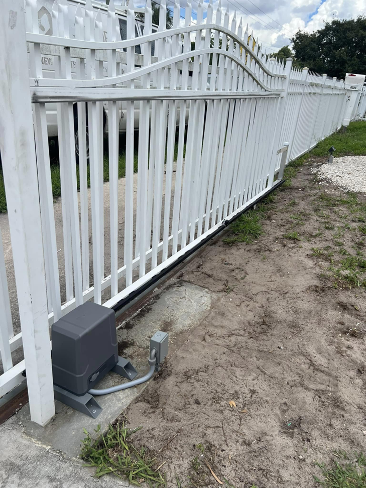 A white picket-style sliding gate with a newly installed gate operator motor by Motor & Fence Solutions in Miami, FL.