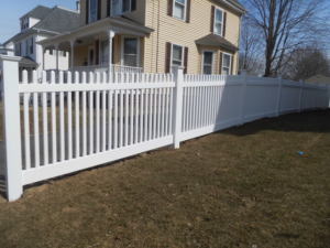 A newly installed white picket vinyl fence enhancing a front yard by Vinyl Fences Inc. in Dover, NH.