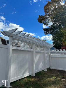 A white privacy fence featuring a decorative lattice top and pergola elements, installed by Teto's Fence Installation in Bridgeport, CT.