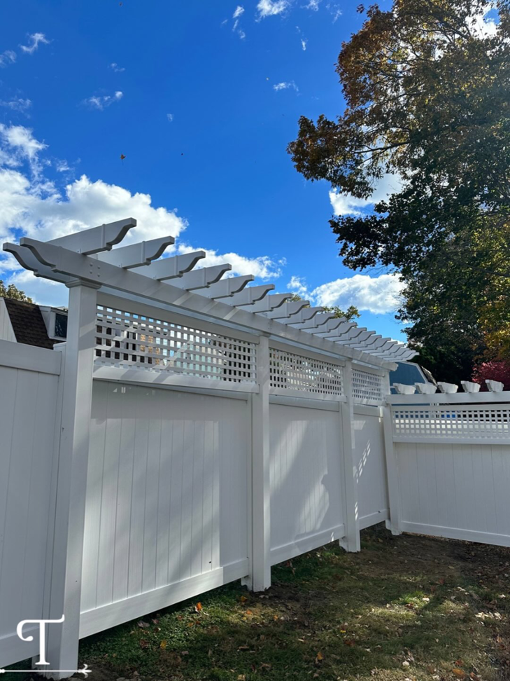 A white privacy fence featuring a decorative lattice top and pergola elements, installed by Teto's Fence Installation in Bridgeport, CT.