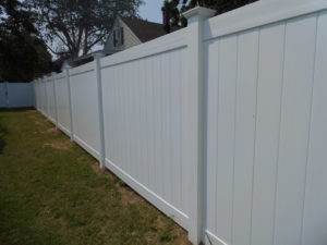 A long white privacy vinyl fence installed in a residential backyard by Vinyl Fences Inc. in Dover, NH.