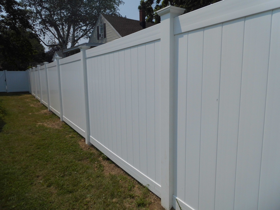A long white privacy vinyl fence installed in a residential backyard by Vinyl Fences Inc. in Dover, NH.