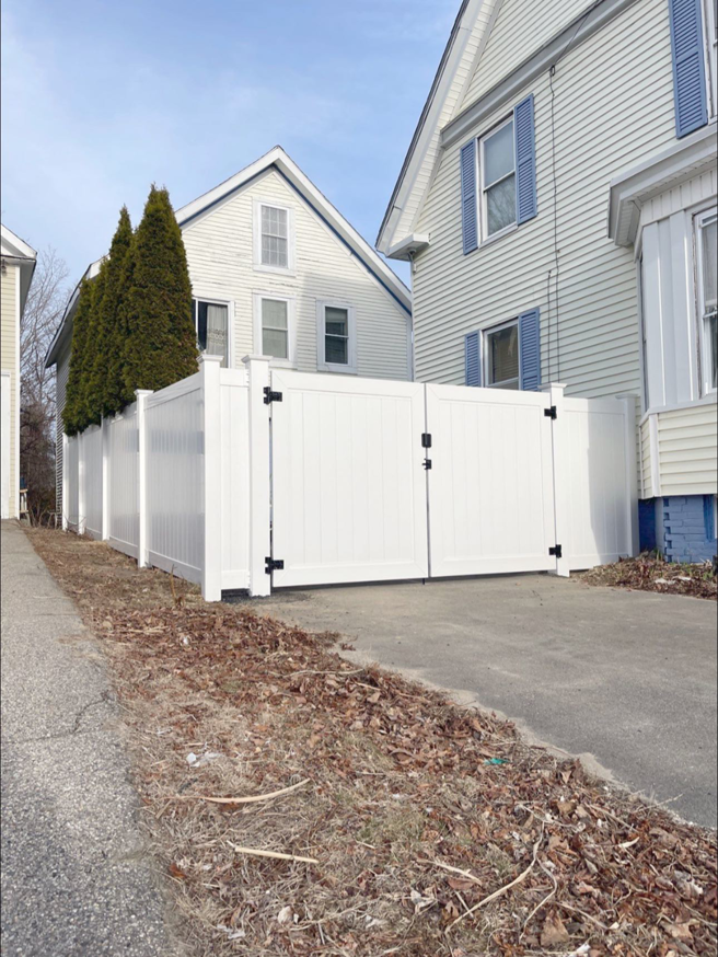 A white privacy vinyl fence with a double gate installed for driveway access by Vinyl Fences Inc. in Dover, NH.