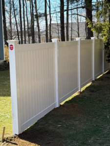 A section of white privacy vinyl fence installed in a residential backyard by Vinyl Fences Inc. in Dover, NH.